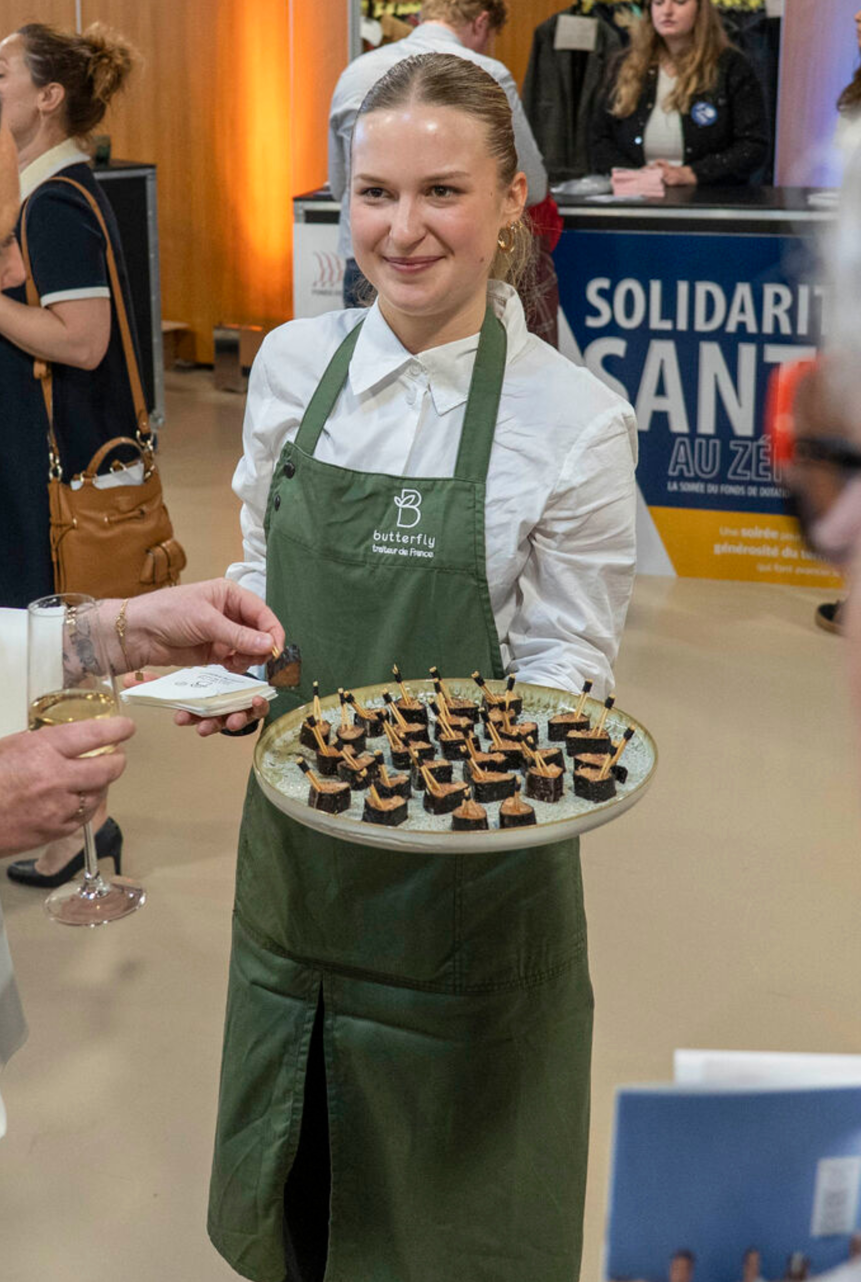 Collaboratrice Butterfly présentant un plateau lors d'un événement solidaire