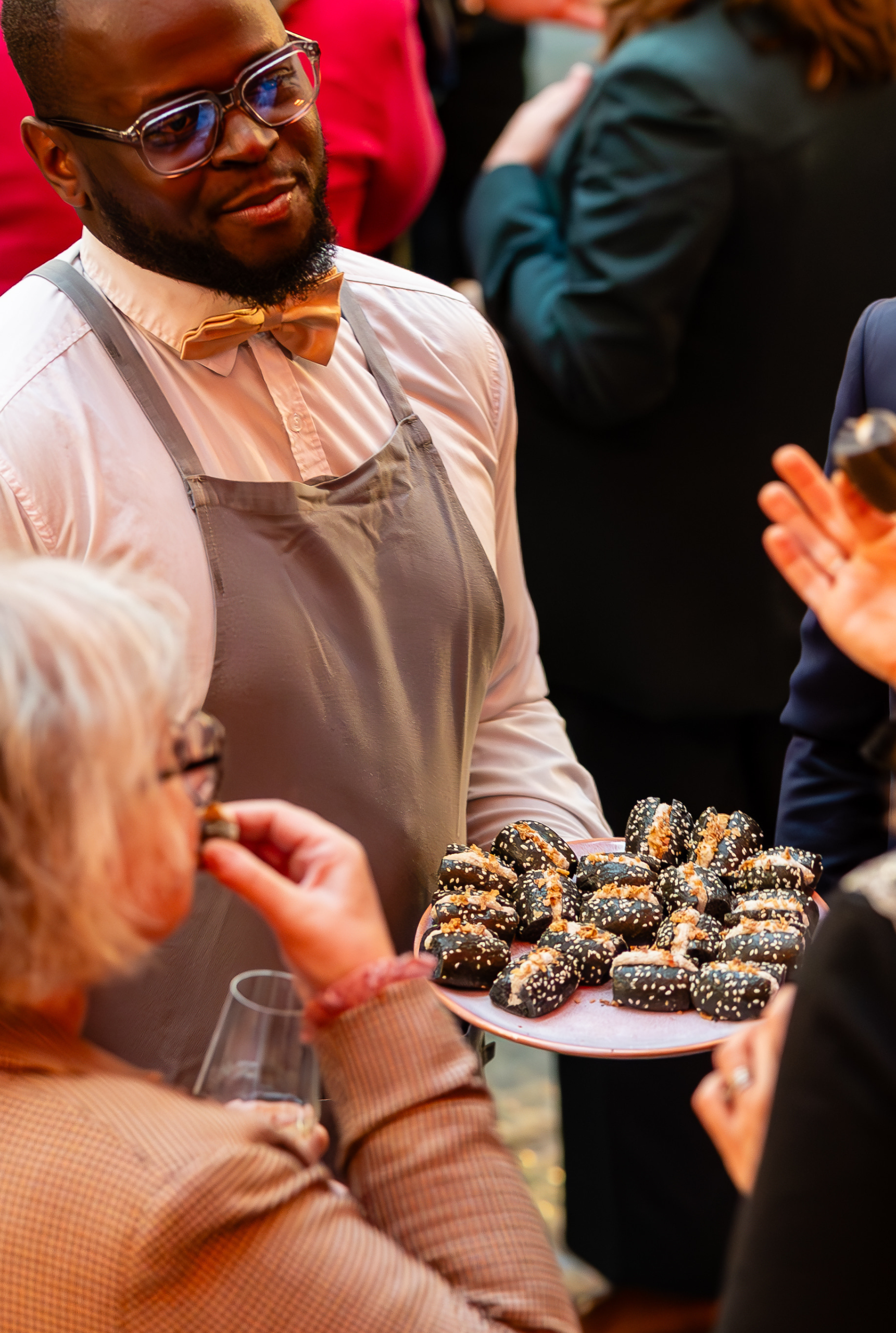 Serveur présentant un plateau de bouchées à des convives