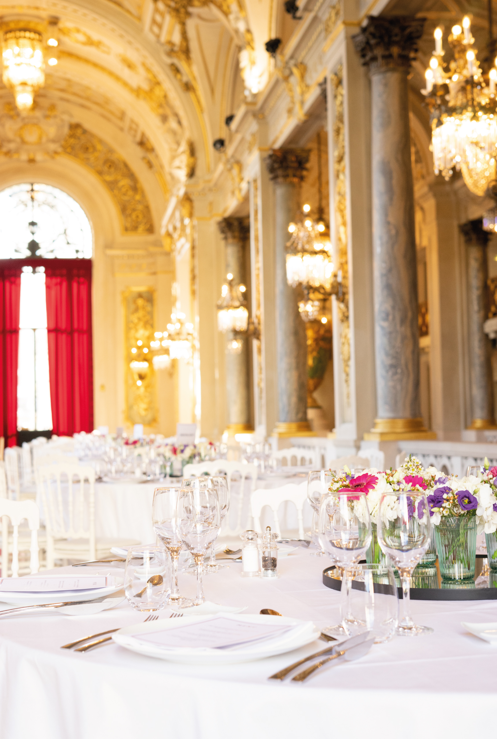 Table ronde dressée en nappe blanche et cristallerie dans un salon doré parisien