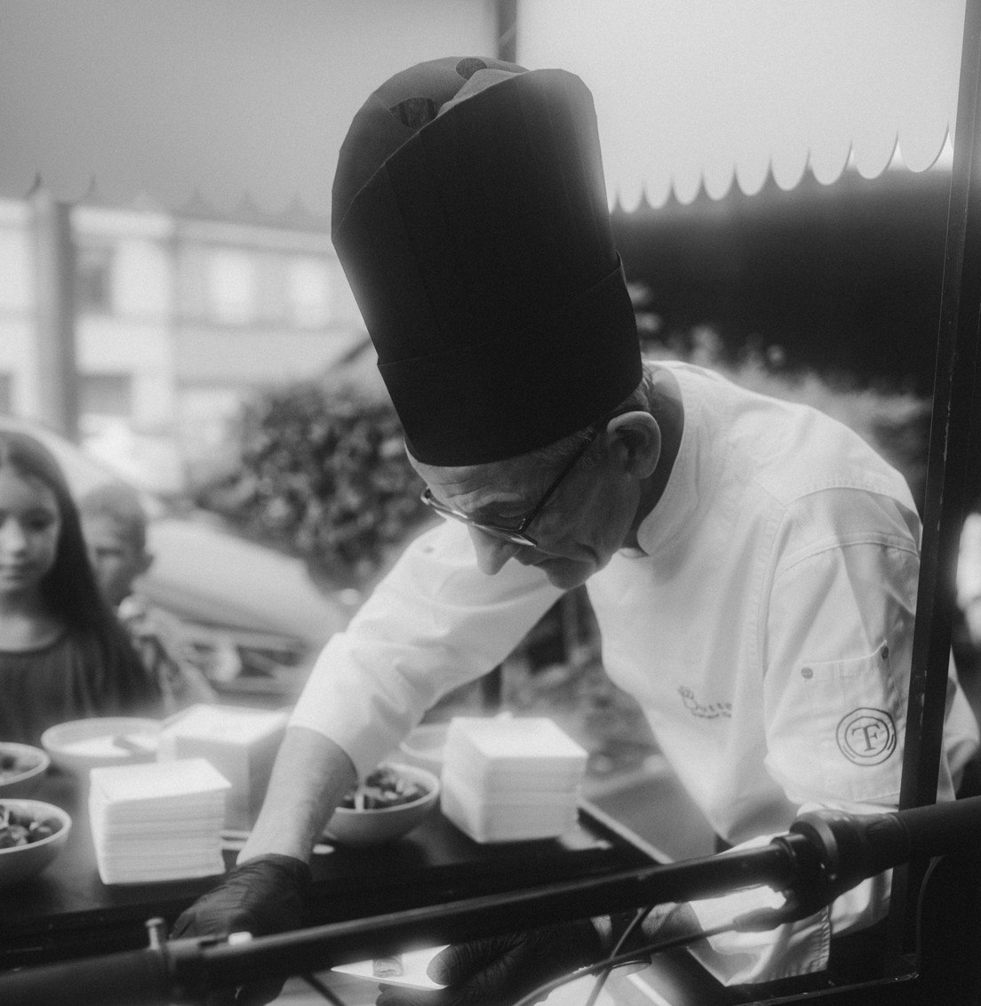 Chef Butterfly Traiteur en toque préparant des assiettes en direct sur un stand d’animation culinaire de mariage